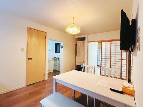 a dining room with a table and a tv and a room at Kokoro no sato・Ume in Kyoto