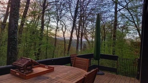 a wooden table and chairs on a deck with a view at Maison Tronchiennes in Durbuy