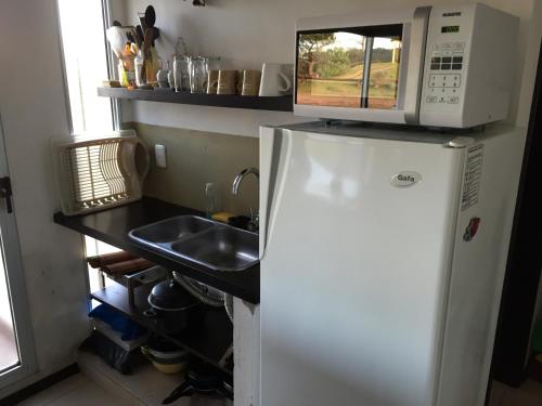 a kitchen with a microwave on top of a refrigerator at Casa de Familia Jiro in Punta Del Diablo