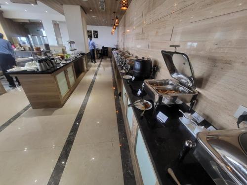 a long counter in a restaurant with a line of dishes at Grand Continent Hosur A Sarovar Portico Affiliate Hotel in Hosūr