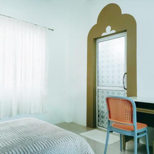 a bedroom with a bed and a chair next to a window at SN Garden in Songkhla