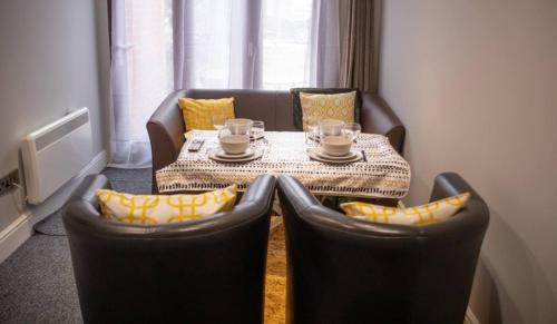 a table with two chairs and a table with cups on it at Stay Norwich Apartments 17colgate in Norwich