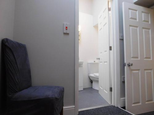 baño con aseo y silla azul en Stay Norwich Apartments 17colgate en Norwich