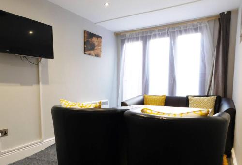 sala de estar con sofá negro y ventana en Stay Norwich Apartments 17colgate en Norwich