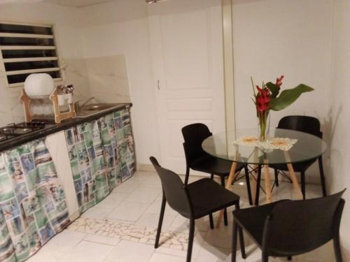 a dining room with a table with chairs and a vase of flowers at Gites coeur des Antilles G in Trois-Rivières