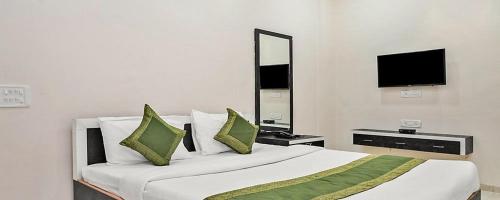 a bedroom with a large white bed with green pillows at Hotel Meghmalhar Lodging in Jejūri