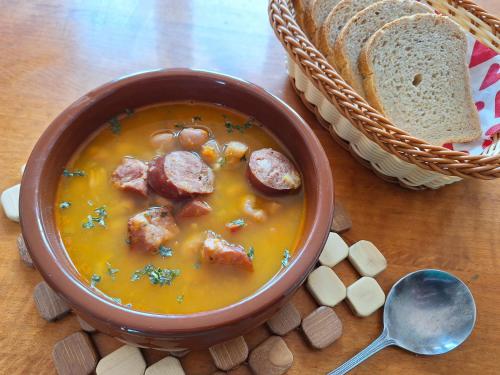 a bowl of sausage soup with a basket of bread at Mill House Apartment and Camping in Ljutomer