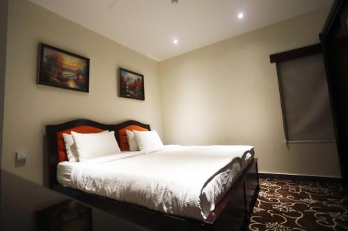 فندق Naylover Suites في عمّان: غرفة نوم بسرير وملاءات بيضاء ومخدات برتقالية
