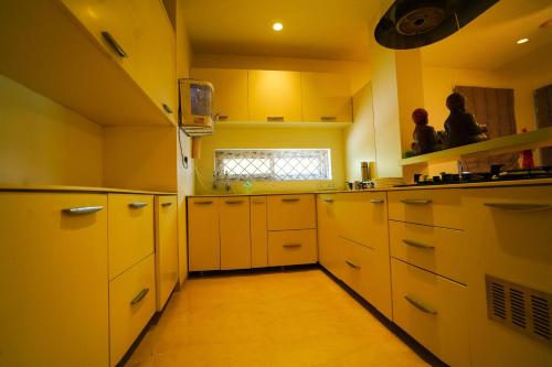 a yellow kitchen with white cabinets and a window at Golden Villa - Duplex House With Private Theater - Near To Alipiri And Bhudevi TTD Ticket Counter And Kapilateertham in Tirupati