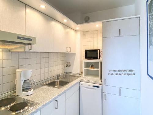 uma cozinha com armários brancos, um lavatório e um micro-ondas em Whg Sturmmöwe - Haus Nordlichter em Wendtorf