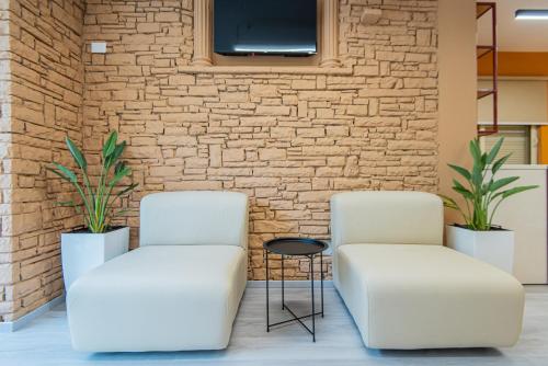 twee witte stoelen naast een stenen muur bij ApartHotel EDA in Durrës