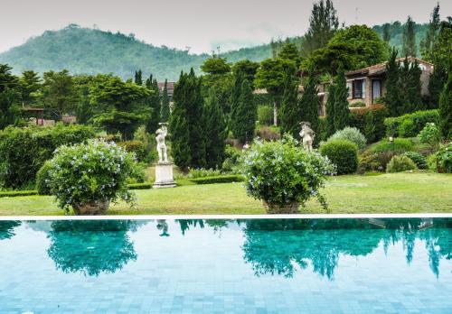 a swimming pool in the middle of a garden at La Toscana in Suan Phung
