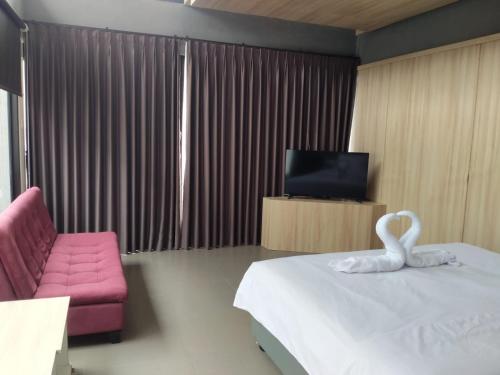 une chambre d'hôtel avec un lit et une chaise rose dans l'établissement Lynn Resort Carita, à Sukarame