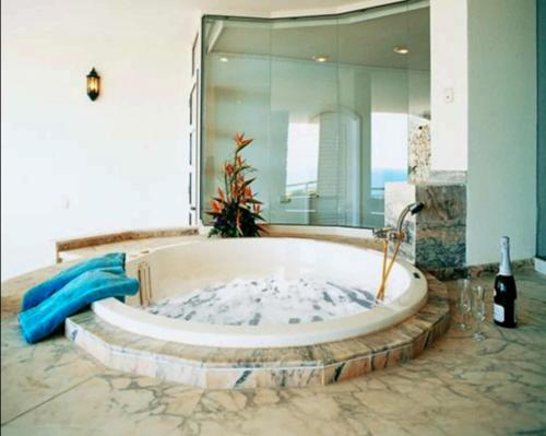a bath tub in a room with a large mirror at Penthouse 3 Bedroom Sleeps 8 With 270 deg Sea Views in Mogán