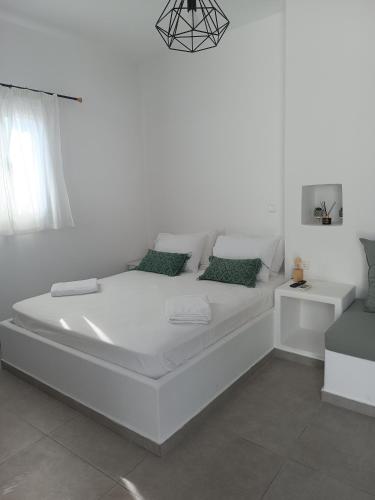 a large white bed in a white room with green pillows at Alma Guesthouse in Kithnos