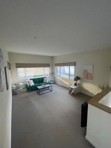 uma sala de estar com um sofá verde e uma mesa em Sea views from sunny house em Wellington