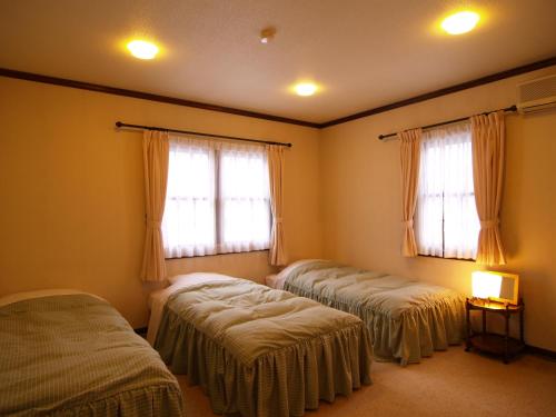 1 dormitorio con 2 camas y 2 ventanas en Pension Syo, en Hakuba