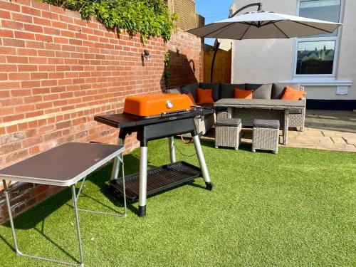 a barbecue grill on a lawn with an umbrella at Dog friendly home close to the beach and the town in Exmouth
