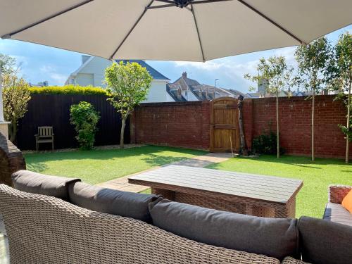 a patio with a couch and a table and an umbrella at Dog friendly home close to the beach and the town in Exmouth