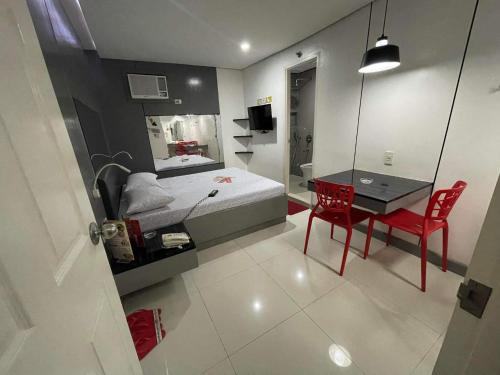 um quarto com uma cama e uma secretária com uma cadeira vermelha em Hotel Sogo Edsa Cubao em Manila