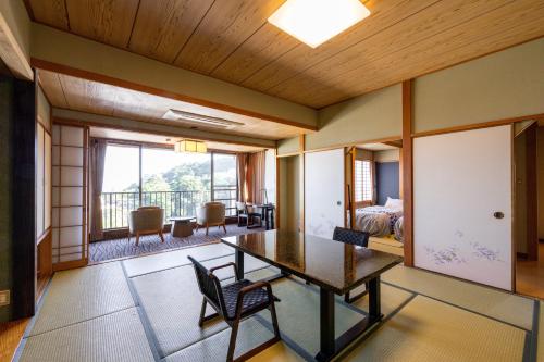 a room with a table and chairs and a balcony at Atagawa Prince Hotel in Higashiizu