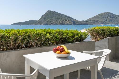 a bowl of fruit on a white table with a view of the ocean at Nelly's Apartments in Tolo