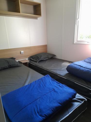 - 2 lits dans une chambre avec des draps bleus dans l'établissement Mobilhome spacieux MH580 3ch et grande terrasse, à Gastes