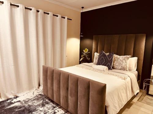 a bedroom with a large bed with a large headboard at Shepherds Inn in Boksburg