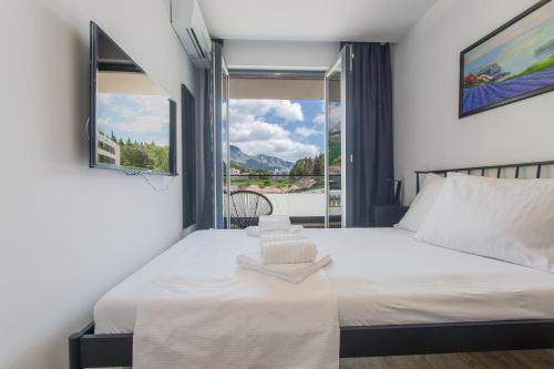 ein Schlafzimmer mit einem großen weißen Bett mit einem Fenster in der Unterkunft Luxury Apartment Monika with Shared Pool in Makarska