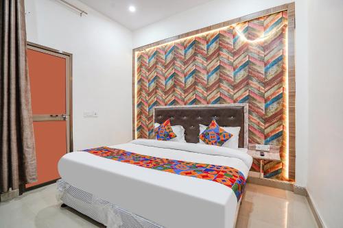 Bett in einem Zimmer mit Wandgemälde in der Unterkunft FabHotel Siya Bihari in Ayodhya