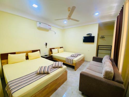 a hotel room with two beds and a couch at Sparkling Resort Kataragama in Kataragama