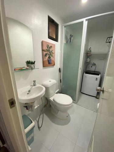 a white bathroom with a toilet and a sink at Royal Oceancrest Mactan - Relaxing Sunset View in Lapu Lapu City
