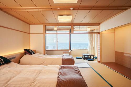 two beds in a room with a view of the ocean at Kaisenkaku in Aomori