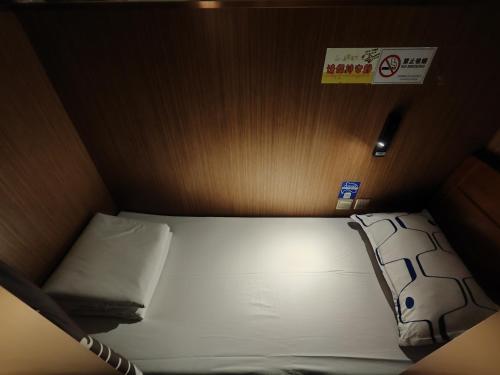 Chengdu Airport Take A Nap Capsule Hotel（T2） في تشنغدو: سرير صغير في غرفة صغيرة مع علامة على الحائط