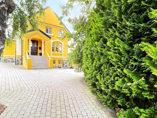 a yellow house with a large green hedge at 10 person holiday home in arendal-By Traum in Arendal