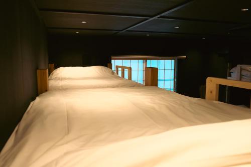 a large white bed in a room with a window at 万雷ホテル in Tokyo