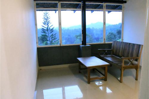 a room with a bench and a table and windows at Mothers Bounty by Lazo , Coorg in Madikeri