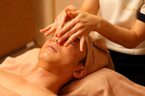 a woman giving a mans head massage in a hospital at Sauna & Capsule Hotel Rumor Plaza in Kyoto