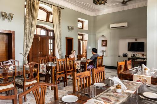 two people sitting at tables in a restaurant at Devnadi Hotel in Haridwār