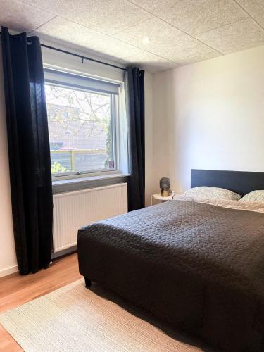 1 dormitorio con cama y ventana grande en The Heart of Billund apartment, en Billund