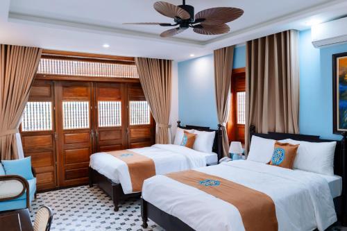a hotel room with two beds and a ceiling fan at 1962 Garden Inn in Hue