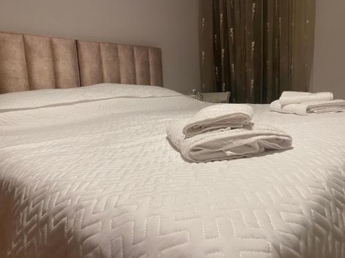 Una cama blanca con toallas encima. en Klik center Apartment, en Tirana