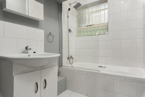 a white bathroom with a sink and a bath tub at The Crazy Central in Cape Town