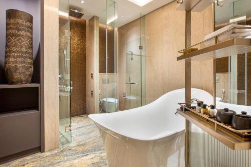 a bathroom with a white tub and a glass shower at MORAZEN Yogyakarta in Temon