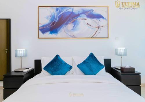 a bedroom with a white bed with blue pillows at Ultima Vacation Homes loft 1 BR Apartment in Dubai