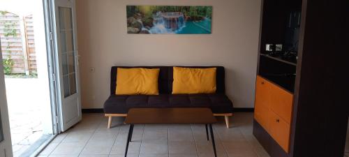 a living room with a couch with two yellow pillows at Vacances martinique in Sainte-Anne