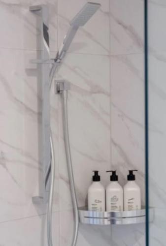 a glass shelf with three bottles of detergent in a bathroom at Riccarton 2 bed 1 bath w/garage in Christchurch
