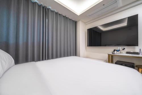 a hotel room with a bed and a flat screen tv at Bluebird Hotel in Incheon
