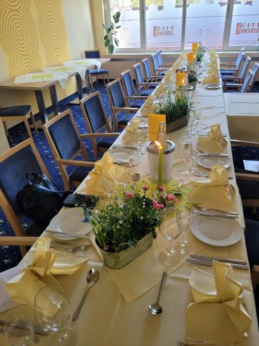 a long table with yellow napkins and wine glasses at City-Hotel Cottbus in Cottbus