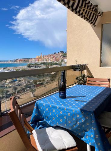 une table avec une bouteille dessus dans une pièce avec une fenêtre dans l'établissement Alloggio fronte mare vista bellissima Mentone Garavan, à Menton